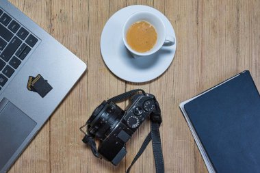 Kameralı tahta masa masası, dizüstü bilgisayar, hafıza kartları, espresso bardağı ve dosya. Yukarıdan görüntüle.