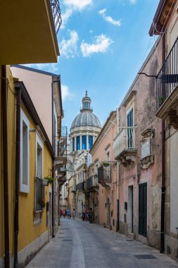 RAGUSA, İtalya - 18 AĞUSTOS 2017: Ragusa 'da eski kasaba evleri ve Sicilya, İtalya' da bir kilisenin kubbesi olan dar manzaralı cadde