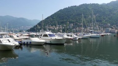 Ördekler Como Gölü marinasında demirlemiş teknelerin arasında yüzerler.