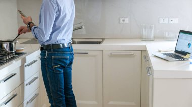 Adam yemek pişirirken, akıllı çalışırken, uzaktan çalışırken dizüstü bilgisayarla çalışıyor.