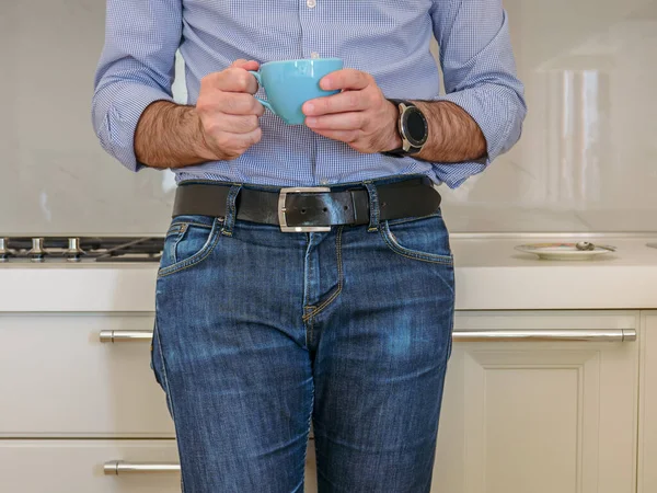 man drinks coffee in a colorful cup in the kitchen