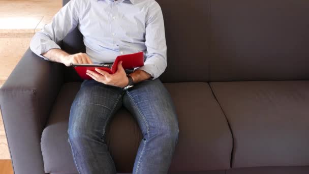 Homem Sentado Sofá Casa Usa Seu Tablet Relaxante Espaço Cópia — Vídeo de Stock