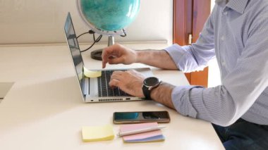 Adam Dünya 'da bir yer arayarak ve dizüstü bilgisayarda araştırma yaparak seyahat etmeyi planlıyor. tatil planlama, tatil, seyahat, rota kavramları.