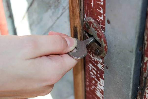 Hand opening the key lock in the old door.