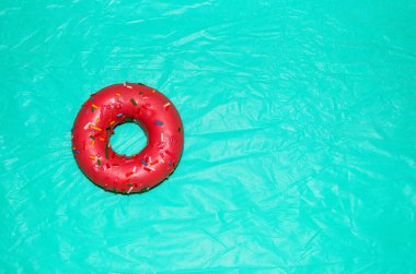 Pembe donut, parlak turkuaz bir arka planda, gökkuşağı şeklinde serpiştirilmiş. Metin için şablon, boşluk.