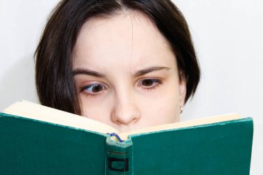 Şaşırmış yüzlü, eski bir kitap okuyan güzel bir kızın büyük bir portresi. Yüzün üst kısmının yakın çekimi..