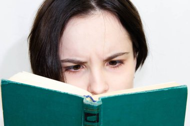 Şaşırmış yüzlü, eski bir kitap okuyan güzel bir kızın büyük bir portresi. Yüzün üst kısmının yakın çekimi..