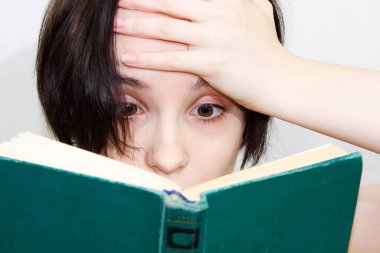 Şaşırmış yüzlü, eski bir kitap okuyan güzel bir kızın büyük bir portresi. Yüzün üst kısmının yakın çekimi..