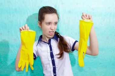 Genç bir kız yüzünde tiksintiyle lastik eldivenler tutuyor. Ortalama plan.