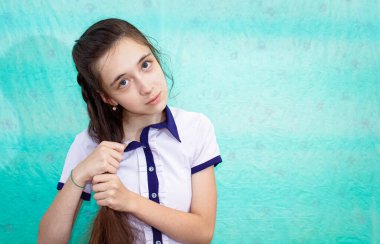 Uzun saçlarını elleriyle düzelten genç bir kızın portresi. Kapat..