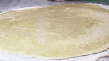 Şekerli kumla serpiştirilmiş ekmek ruloları hazırlamak için hamur işi yuvarlandı. Seçici odak.