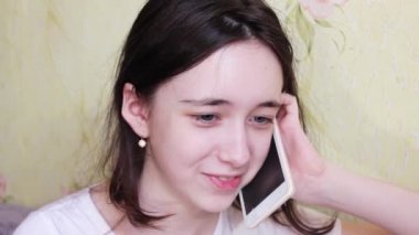 Evde genç bir kız telefonda konuşarak eğleniyor. Kapat..