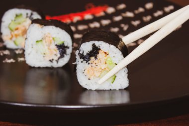 Çubuklarda somon balığı ve taze salatalık var. Makro, yakın çekim, seçici çekim.