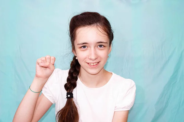 一个长辫子的女孩用她的手用聋哑人的手语展示了字母S 中期计划 绿松石背景 — 图库照片