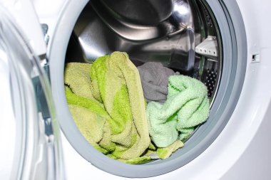 İçinde kirli çamaşırların gömülü olduğu açık bir çamaşır makinesi. Yakın çekim, seçici odaklanma.