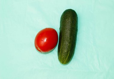 Olgunlaşmış salatalık ve domates turkuaz arka planda. Yukarıdan görünüşü.