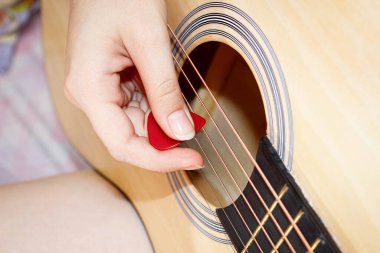 Bir kadının eli tellerde gitar penası çalar. Yakın çekim, seçici çekim.