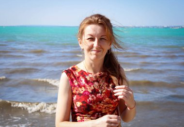 Kızıl saçlı ve çilli güzel bir kadın kumsalda gülümsüyor. Kapat..