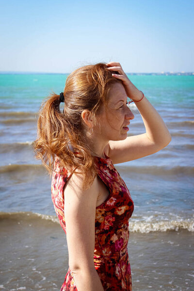A worried woman is waiting for someone on the beach. Close-up, vertical frame.