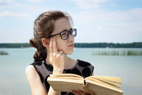 Una Chica Con Gafas Refleja Mientras Lee Libro Sentado Junto —  Fotos de Stock