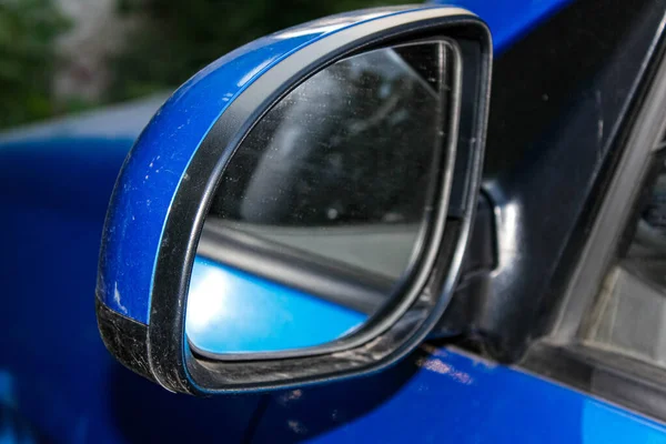Dirty left side view mirror close - up of a blue car. Close-up, selective shot.