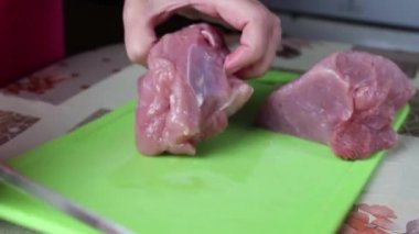 Ev hanımı mutfakta kesme tahtasında çiğ et keser. Yakın çekim, seçici odaklanma.
