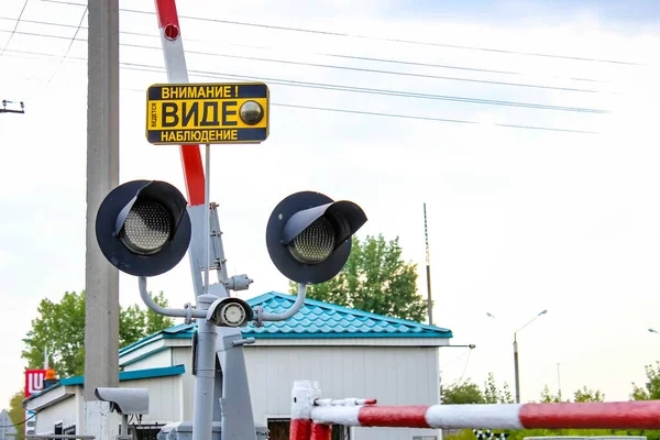 A railway crossing with a traffic light, barrier and sign in Russian. Close up.