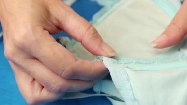 Kadın mavi sütyen kasesinden çıkan demir sütyen kemiğini yerleştiriyor. Kapat..