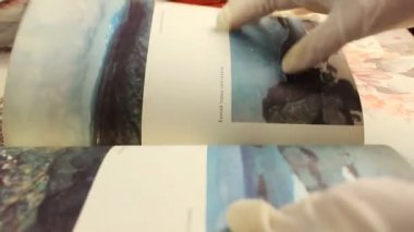 Chelyabinsk, Rusya-23 Ağustos 2020: Tek kullanımlık eldivenli bir adam eski tozlu dergileri Rus metniyle yorumluyor. Seçici atış.