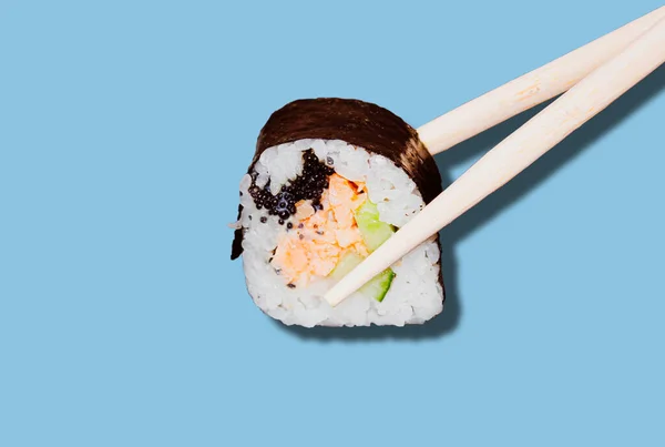 Wooden Sticks that hold a sushi roll on a blue background. — Stock Photo, Image