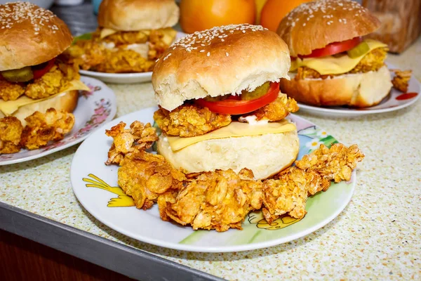 Several burgers and breaded fillets on plates. Close up.