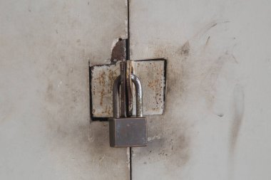 Kapı eski metal bir kilitle kapatılmış. Paslı gri metal kapıdaki çelik kilit. yakın plan.