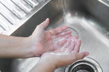Ellerini yıkayan adam lavaboda akan suyla sabunu duruluyor, Coronavirus önleyici el hijyeni. Corona Virüsü sık sık ellerini temizleyerek salgın hastalıktan korunuyor..