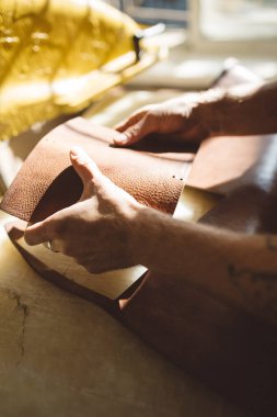  Masada kahverengi deriyle çalışan bir adamın ellerini kapatın.