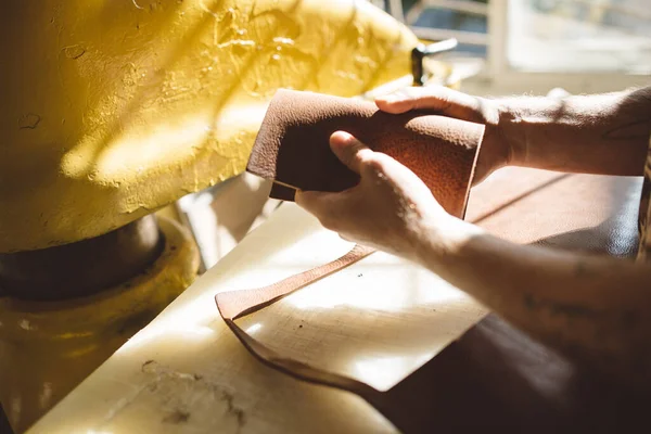 stock image  close up hands of a man working with brown leather on the table