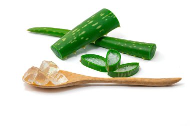 Su damlaları Aloe Vera 'yı (Aloe barbadensis Mill, Star cactus, Aloe, Aloin, Jafferabad veya Barbados) keser ve kesme yolu olan beyaz bir arka planda izole edilmiş ahşap kaşığa jel sürer.