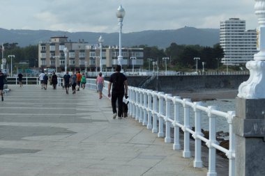 Gijon 'da deniz kenarında yürüyen insanlar.