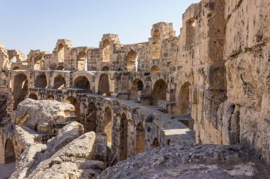 Tunus 'taki El Jem antik Roma amfitiyatrosunun etkileyici görüntüsü ve açık mavi gökyüzüne doğru uçan kuşlar.
