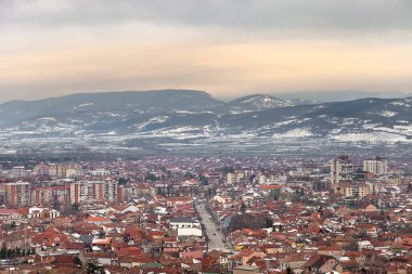 Sırbistan 'ın Pirot şehrinin güzel günbatımı manzarası, karla kaplı uzak ufuk dağlar ve karanlık, bulanık bulutların altında altın gökyüzü