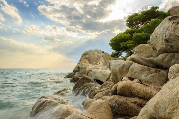 太陽の光が雲の中を通り コヴィウビーチのターコイズブルーの海の水と美しい岩に落ちる — ストック写真