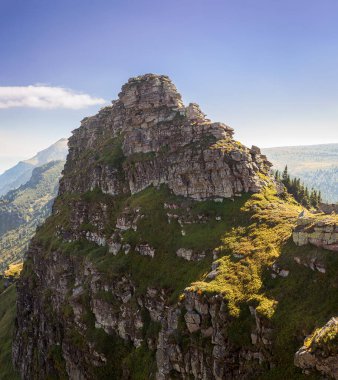 Sırbistan ve Bulgaristan sınırındaki Eski Dağ 'ın etkileyici sivri, kayalık, dik zirvesi Tri Cuke bir güneş ışınıyla aydınlanıyor