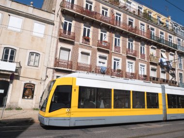 Eski binaların yakınındaki raylar üzerinde çalışan modern sarı tramvay