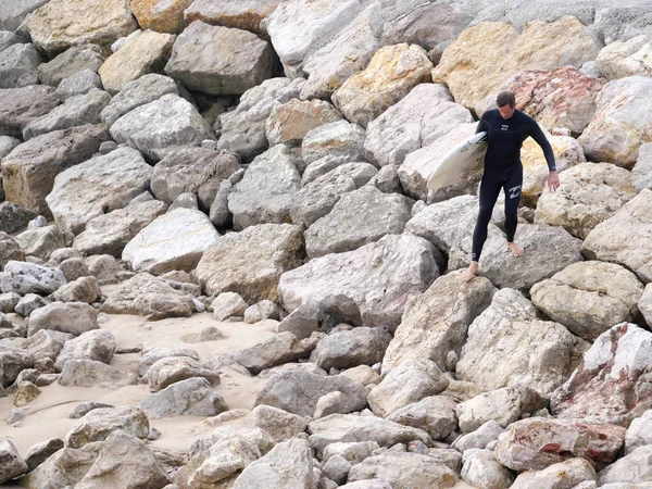 bir okyanus sahilinde sörf tahtası taşıyan sörfçü insanlar