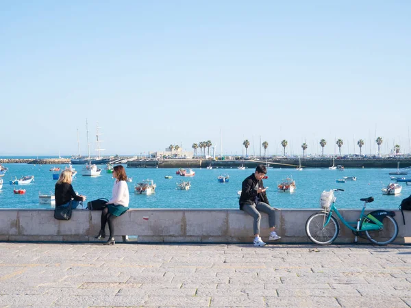 İnsanlar bir sahil parapet üzerinde wakling ve Lizbon'da bir deniz ve köprü arıyor