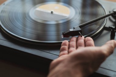 Bir el vinildeki iğneyi yerleştirdi.