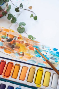 Fırça ile suluboya palet ve bir bitki ile soyut vuruşlar
