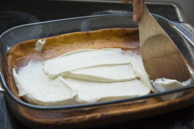 Fırında pişmiş peynirli kekin üzerine krem şanti sürüyorum.