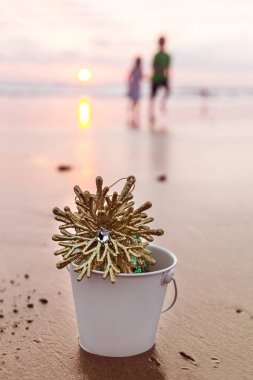 Golden Snowflake In A White Bucket On The Beach At Christmas Sunset In California clipart