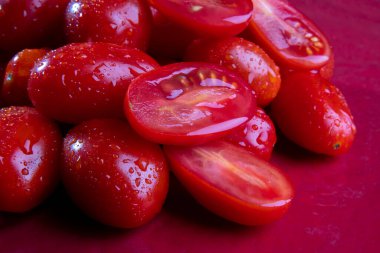 Makro ve bir sürü olgun domates ve sulu vişneli domates kes. Parlak parlak kırmızı üzerine su damlıyor. Metin için alanı olan yiyecek arkaplanı