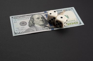 Para, finans ve kumar konsepti: 100 dolarlık banknotun üstüne Benjamin Franklin portresi. 1 ve 2 numaralı paralara iki beyaz zar. Kopyalama alanı olan siyah arkaplan